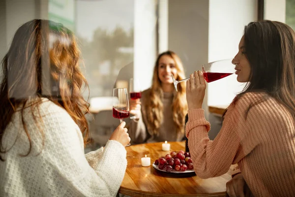 Portret trzech pięknych kobiet jedzących lunch ze szklanką czerwonego wina w jasny dzień — Zdjęcie stockowe