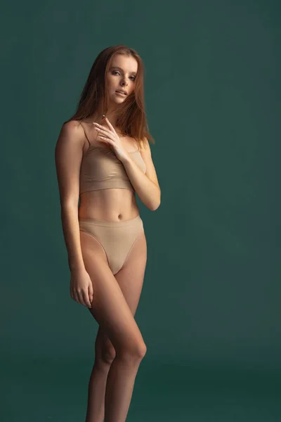 Full-length portrait of beautiful tender woman posing in beige underwear isolated over green background. Femininity — Stock Photo, Image