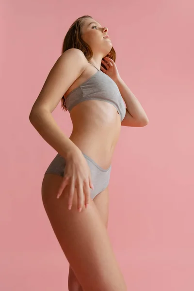 Cropped portrait of beautiful young woman in gray underwear posing isolated over pink background. — Stock Photo, Image