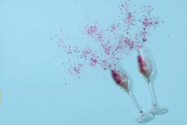 Dos flautas de champán con confeti en el interior sobre fondo de papel azul. Celebración de Año Nuevo — Foto de Stock