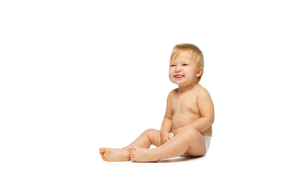 Retrato de pequeño niño lindo, bebé en pañal sentado aislado sobre fondo blanco del estudio. Haciendo caras graciosas — Foto de Stock