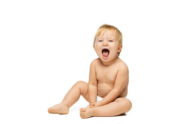 Retrato de pequeño niño lindo, bebé en pañal sentado aislado sobre fondo blanco del estudio. Riéndose, niño alegre — Foto de Stock
