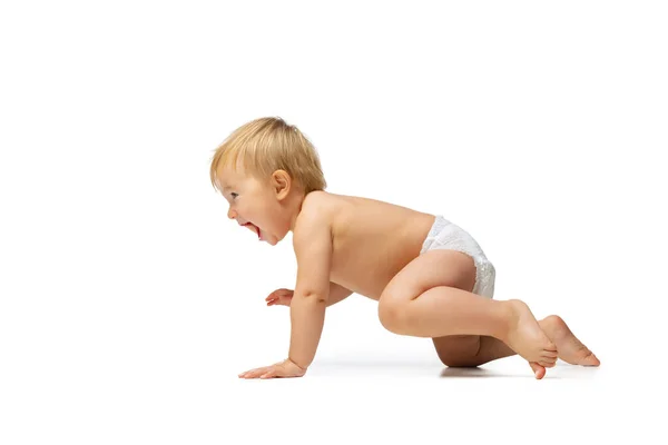 Retrato de pequeño niño lindo, bebé en pañal arrastrándose aislado sobre fondo blanco del estudio. Vista lateral — Foto de Stock