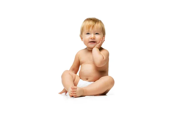 Portret małego słodkiego maluszka, dziecka w pieluszce siedzącego samotnie nad białym tłem studia — Zdjęcie stockowe