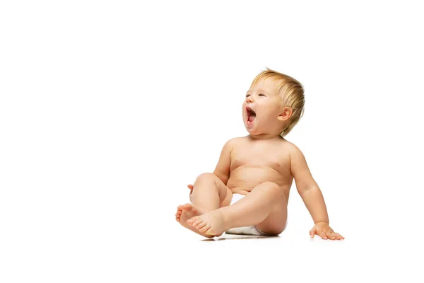 Retrato de pequeño niño lindo, bebé en pañal sentado aislado sobre fondo blanco del estudio. Niño bostezando. — Foto de Stock