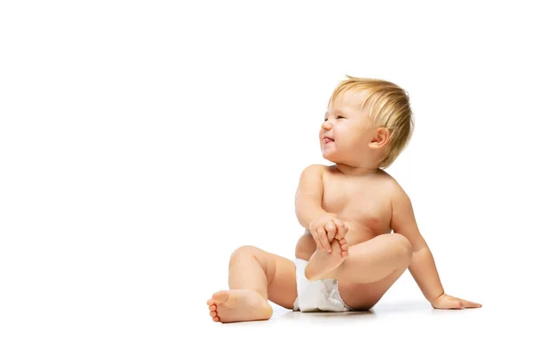Portret małego słodkiego maluszka, dziecka w pieluszce siedzącego samotnie nad białym tłem studia — Zdjęcie stockowe