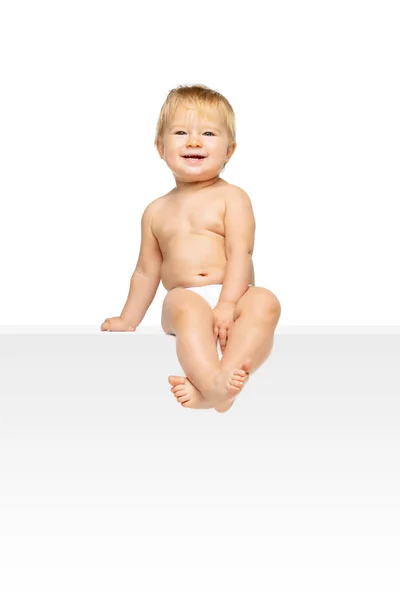 Portrait of little cute toddler boy, baby in diaper sitting isolated over white studio background. Attentive child. — Stock Photo, Image