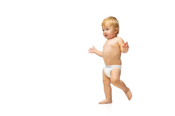 Retrato de un niño pequeño y lindo, bebé en pañal caminando aislado sobre fondo blanco del estudio. Primeros pasos — Foto de Stock