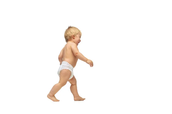 Portrét malého roztomilého batolete chlapce, dítě v plenkách kráčející izolované po bílém pozadí studia. První kroky — Stock fotografie