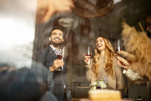 Przycięty portret śmiejących się przyjaciół świętujących wydarzenie w kawiarni, brzęczące kieliszki do wina, wznoszące toast — Zdjęcie stockowe