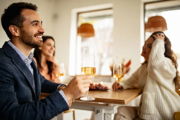 Portret uśmiechniętego mężczyzny pijącego białe wino, mającego radosne spotkanie z przyjaciółmi w kawiarni w ciepły słoneczny dzień — Zdjęcie stockowe