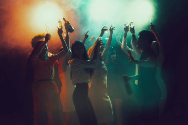 Gece kulübünde bir grup genç ve aktif insan neon ışıklarda dans ediyor.