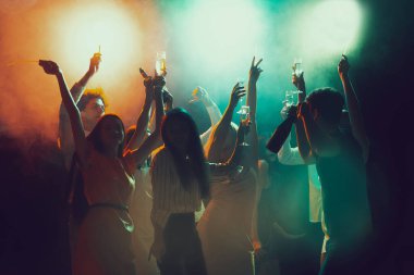 Gece kulübünde bir grup genç ve aktif insan neon ışıklarda dans ediyor.
