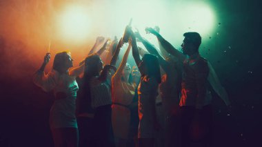 Gece kulübünde bir grup genç ve aktif insan neon ışıklarda dans ediyor.