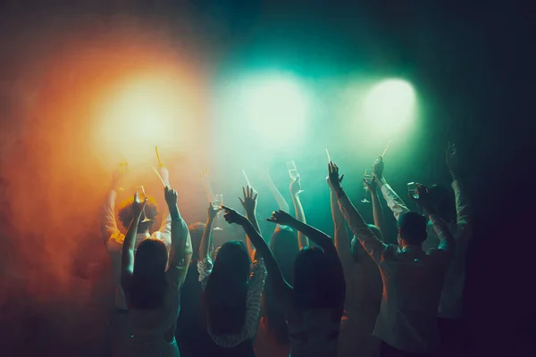 Group of young, active people at the night club, party dancing in neon lights