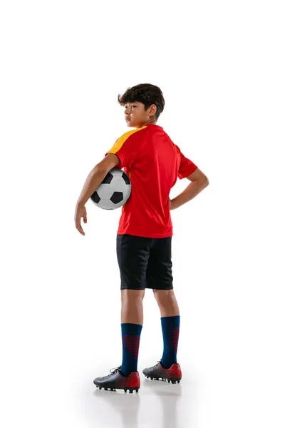 Retrato de vista lateral de cuerpo entero del joven, adolescente, futbolista profesional en uniforme con la pelota posando aislada sobre fondo blanco —  Fotos de Stock
