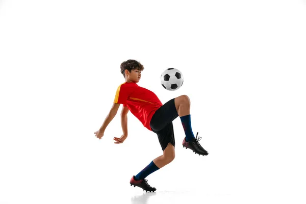 Retrato de niño, adolescente, futbolista profesional en movimiento, kincking una pelota con rodilla aislada sobre fondo blanco —  Fotos de Stock