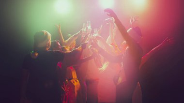 Gece kulübünde bir grup genç ve aktif insan neon ışıklarda dans ediyor. Mutlu yıllar.