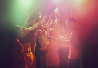 Gece kulübünde bir grup genç ve aktif insan neon ışıklarda dans ediyor. İyi tatiller.