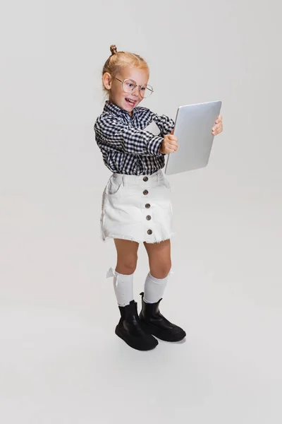 Portret uroczej dziewczynki uśmiechniętej na laptopie odizolowanej na szarym tle — Zdjęcie stockowe
