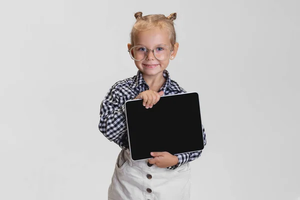 Cropped portrait of cute little girl with tablet isolated over gray background. Boss kid — Stock Photo, Image