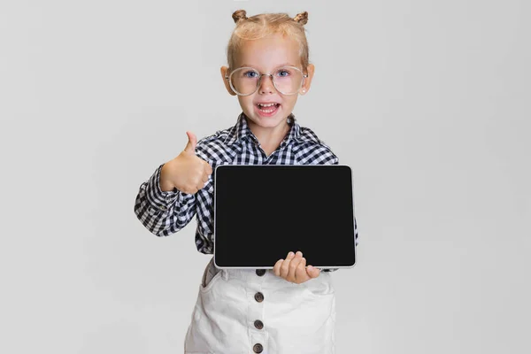 Cropped portrait of cute little girl with tablet isolated over gray background. Boss kid — Stock Photo, Image