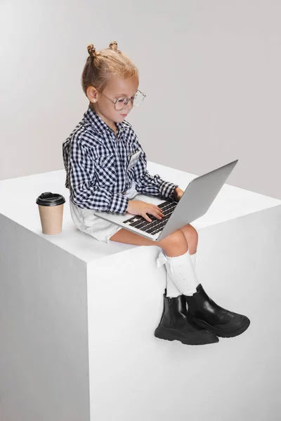 Cropped portrait of cute little girl typing on laptop isolated over gray background — Stock Photo, Image