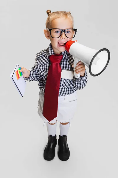 Cropped portrait of cute little girl in casual clothing shouting in megaphone isolated over gray background — Stock Photo, Image