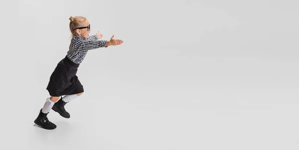 Gehakt portret van een schattig meisje dat geïsoleerd over een grijze achtergrond loopt. Vlieger — Stockfoto