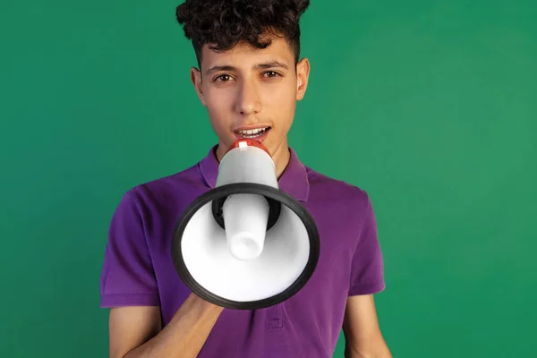 Retrato recortado de un niño joven en camiseta púrpura hablando en megáfono aislado sobre fondo verde —  Fotos de Stock