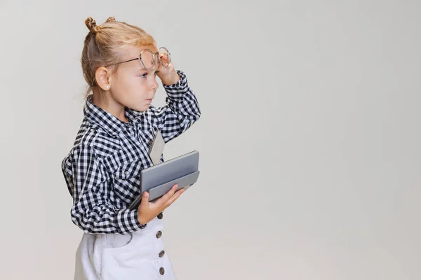 Retrato de vista lateral recortada de niña linda, niño en falda y camisa a cuadros con calculadora aislada sobre fondo gris — Foto de Stock