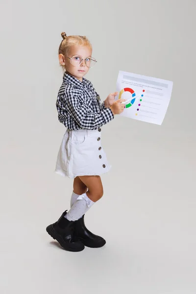 Portret małej dziewczynki, dziecka w spódnicy i koszuli w kratkę pokazujący schemat gdzieś na szarym tle — Zdjęcie stockowe