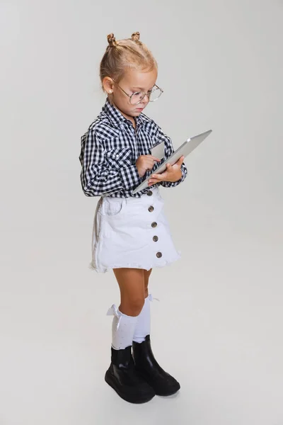 Retrato de vista lateral cortada de menina bonito em roupas casuais e óculos elegantes isolados sobre fundo cinza — Fotografia de Stock