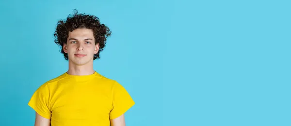 노란 티셔츠를 입은 젊은 남자의 사진 이 파란 배경에 고립되어 있습니다. 진지하고 차분 한 표정. 플라이어 — 스톡 사진