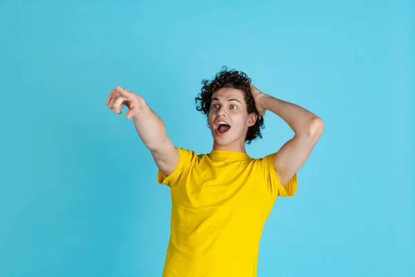 Ausgeschnittenes Porträt eines aufgeregten jungen Mannes in gelbem T-Shirt, das irgendwo isoliert auf blauem Hintergrund zeigt — Stockfoto