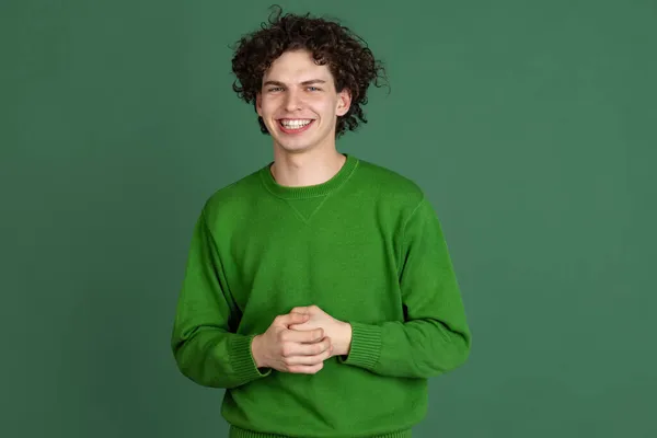 Περικοπή πορτρέτο του νεαρού άνδρα σε πράσινο πουλόβερ χαμογελώντας απομονωμένο σε σκούρο πράσινο φόντο — Φωτογραφία Αρχείου