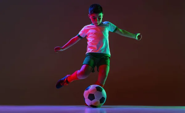 Ganzes horizontales Porträt von Jungen, Kindern und Fußballern, die isoliert über einem Gefällehintergrund in Neonlicht trainieren. Dribbeln — Stockfoto
