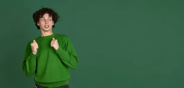 Retrato recortado de jovem em camisola verde com expressão facial assustada isolada sobre fundo verde escuro. Folheto — Fotografia de Stock