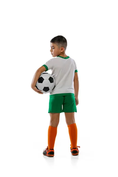 Retrato retrovisor completo de niño, niño, jugador de fútbol en uniforme posando con pelota aislada sobre fondo blanco. —  Fotos de Stock