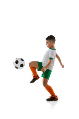 Erkek çocuk portresi, futbol oynayan çocuk, beyaz arka planda izole edilmiş eğitim. Dizinle topa vuruyorsun.
