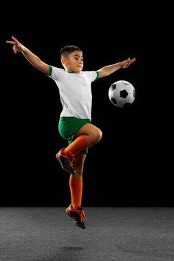 Siyah arka planda izole edilmiş çocuk, çocuk, üniformalı futbolcu portresi..