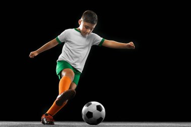 Siyah arka planda izole edilmiş çocuk, çocuk, üniformalı futbolcu portresi..