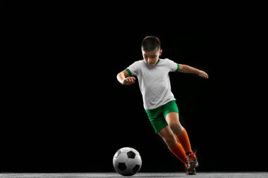Siyah arka planda izole edilmiş çocuk, çocuk, üniformalı futbolcu portresi. Penaltı atışı