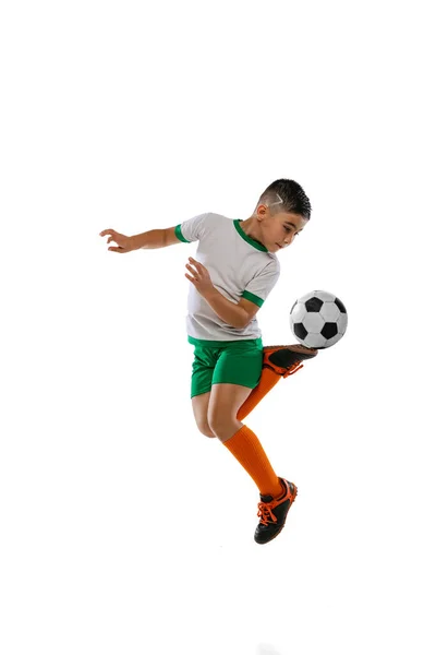 Retrato completo de niño, niño, jugador de fútbol en entrenamiento uniforme, pateando la pelota en un salto aislado sobre fondo blanco. Hacer talón trasero —  Fotos de Stock
