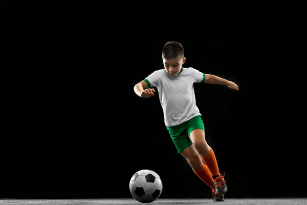 Ολο το μήκος πορτρέτο του αγοριού, του παιδιού, ποδοσφαιριστής σε ομοιόμορφη εκπαίδευση απομονώνονται σε μαύρο φόντο. Ποινή — Φωτογραφία Αρχείου