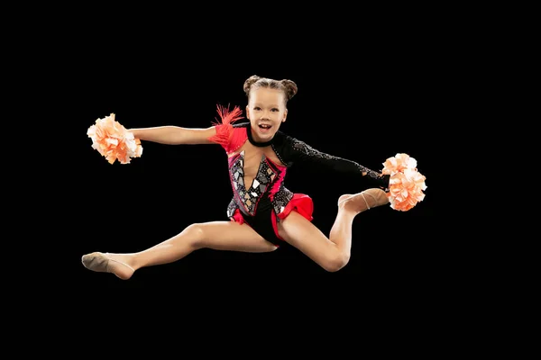 Retrato completo de menina bonita, treinamento de líder de torcida, fazendo movimentos em um salto isolado sobre fundo preto — Fotografia de Stock