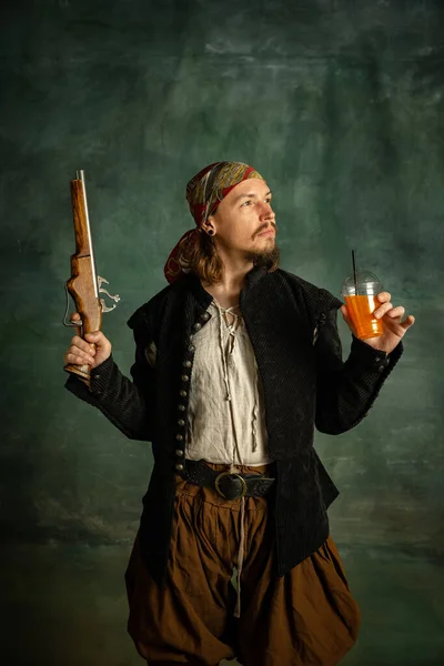 Portré egy brutális ember, középkori kalóz emelés pisztoly és narancslé elszigetelt sötét háttér. — Stock Fotó