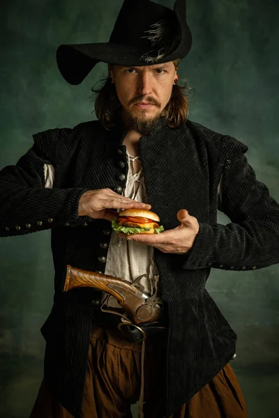 Портрет однієї жорстокої людини, піратський бургер, що стискає бургер ізольовано на темному тлі . — стокове фото