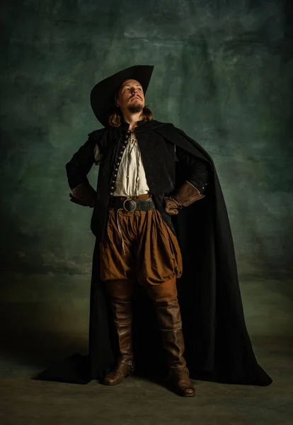 Retrato de cuerpo entero de gentil hombre brutal, pirata medeival con sombrero y capa con espada aislada sobre fondo oscuro. — Foto de Stock