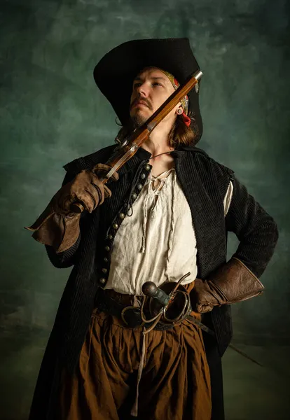 Retrato recortado de hombre brutal, pirata medeival en traje vintage con pistola, pistola aislada sobre fondo oscuro. — Foto de Stock